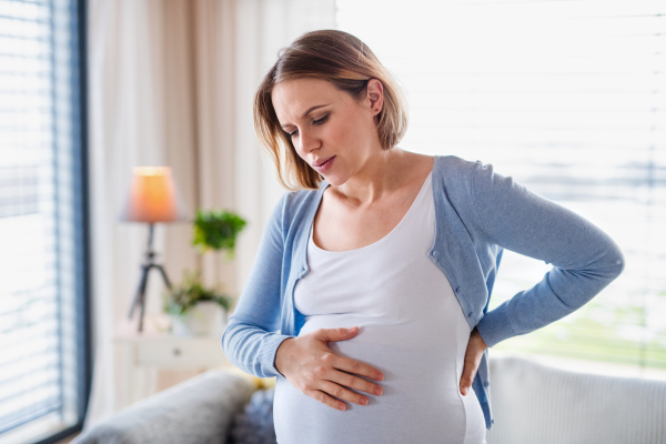 A portrait of pregnant young woman indoors at home, feeling tired.