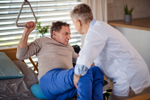 A healthcare worker helping paralysed senior patient in wheelchair in hospital.