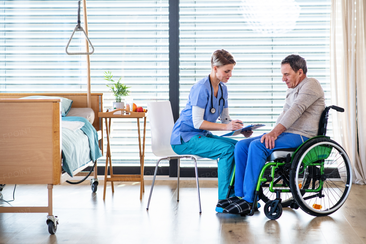 A healthcare worker and senior patient in wheelchair in hospital or at home, talking.