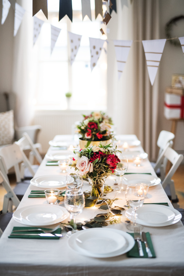 A table set for a meal indoors in a room on a party, a wedding or family celebration.