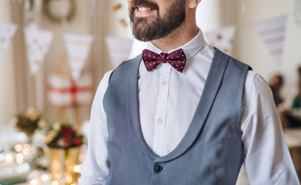 A midsection of man standing indoors in a room set for a party.