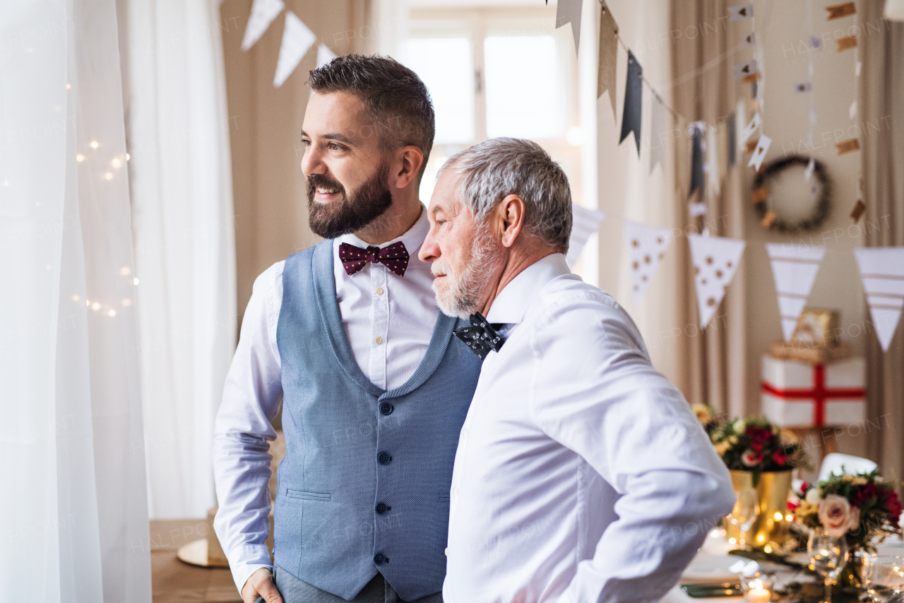 A portrait of a senior and hipster mature man standing indoors in a room set for a party.