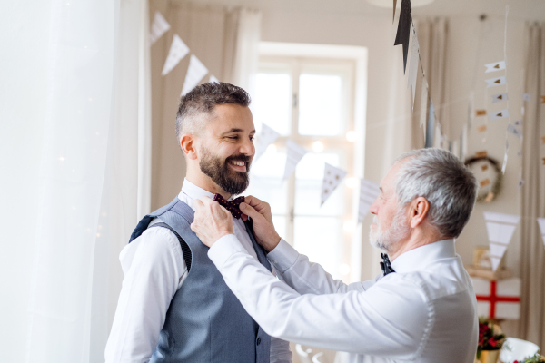 A portrait of a senior and hipster mature man standing indoors in a room set for a party.