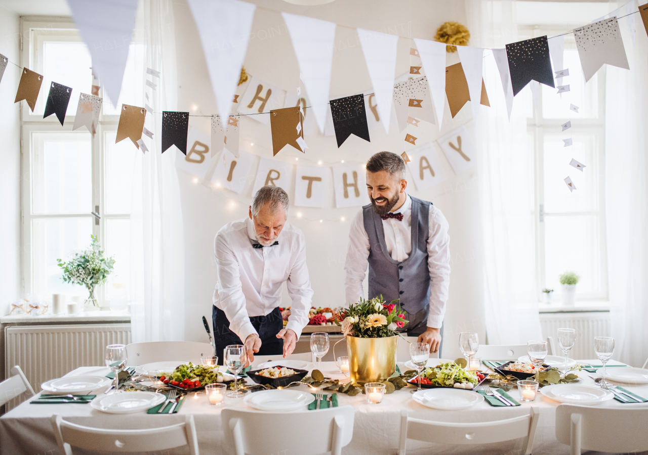 A portrait of a senior and hipster mature man standing indoors in a room set for a party, talking.