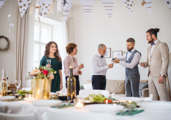 A man pouring happy guests wine on a indoor family birthday party.