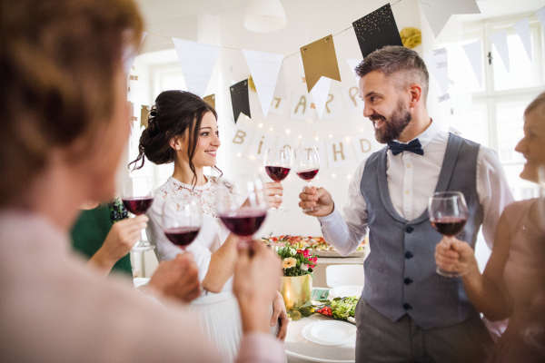 A multigeneration family clinking glasses with red wine on a indoor family birthday party, making a toast.