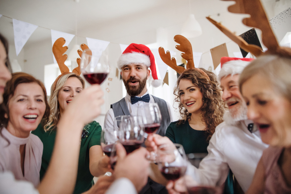 A group of friends with reindeer headband and santa hat clinking glasses on a indoor party.