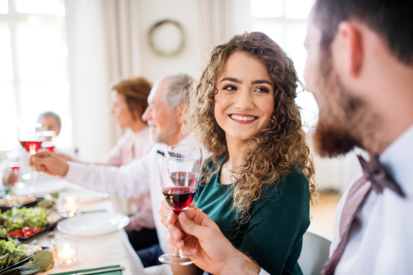 A young cheerful couple sitting at a table on a indoor birthday party, clinking glasses.