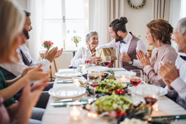 An elderly grandmother in a wheelchair celebrating birthday with family, a party concept.