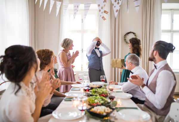 A young woman giving gift to a mature man on a family birthday party.