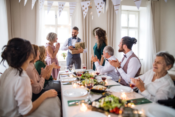 A young couple giving a gift to an old mother on a family birthday party.