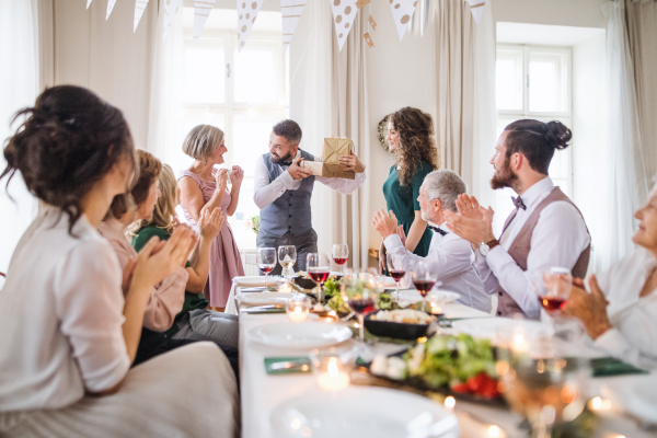 A young woman giving gift to a mature man on a family birthday party.