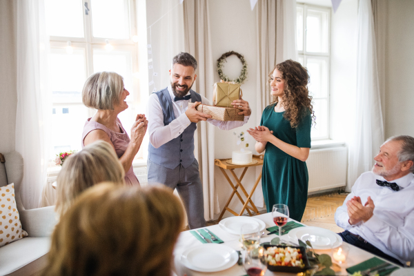 A young couple giving a gift to an old mother on a family birthday party.