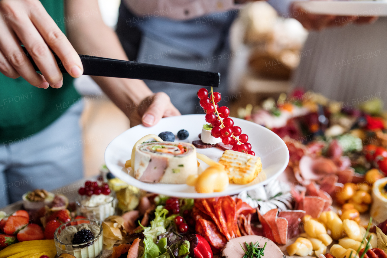 Midsection of a woman putting food on a plate on a indoor family birthday party.