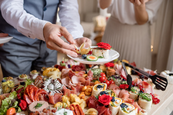 Midsection of a man putting food on a plate on a indoor family birthday party.