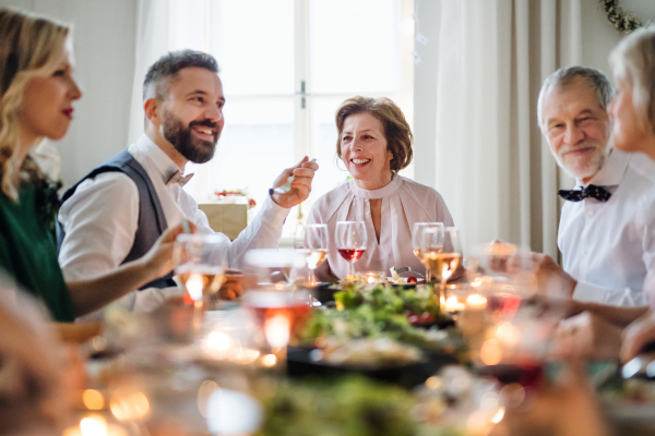 A happy big family sitting at a table on a indoor birthday party, eating.