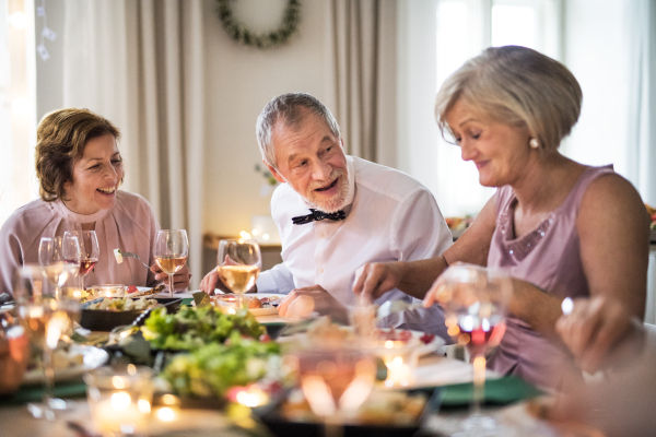 Cheerful seniors sitting at the table on a indoor family birthday party, eating.