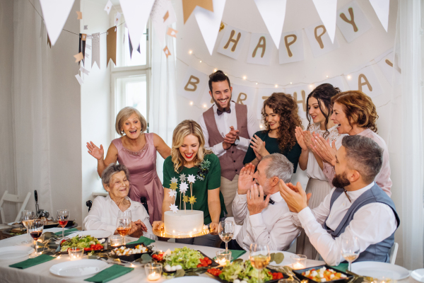 A senior man with multigeneration family and a cake celebrating birthday on an indoor party.