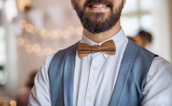 A midsection of man standing indoors in a room set for a party.