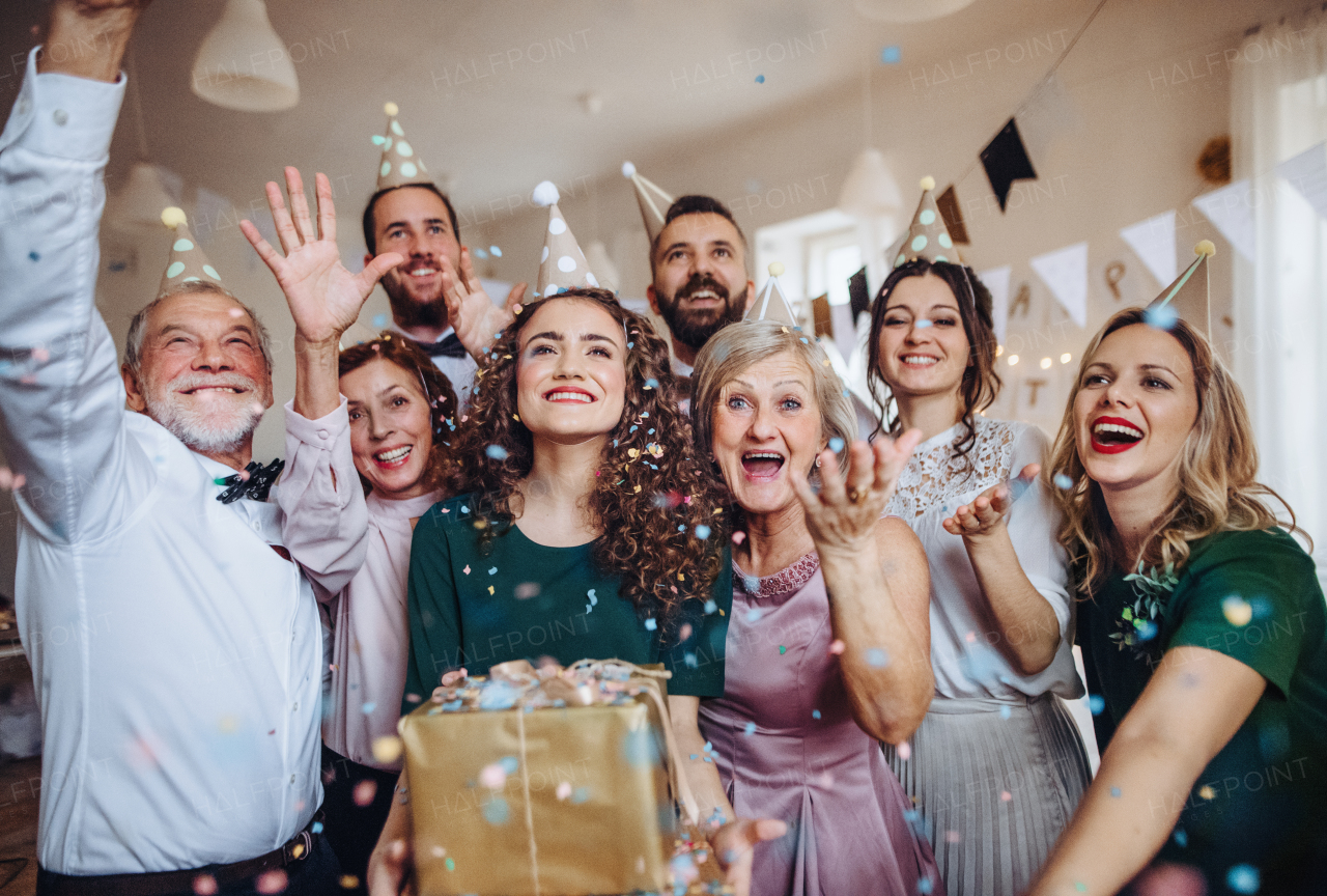 A portrait of multigeneration family with presents standing indoor on a birthday party.