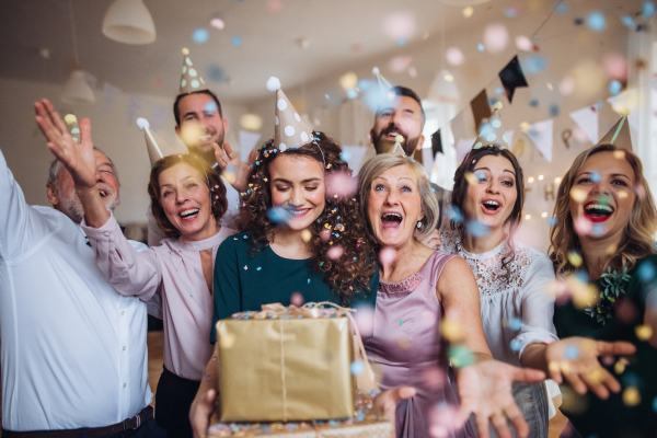 A portrait of multigeneration family with presents standing indoor on a birthday party.