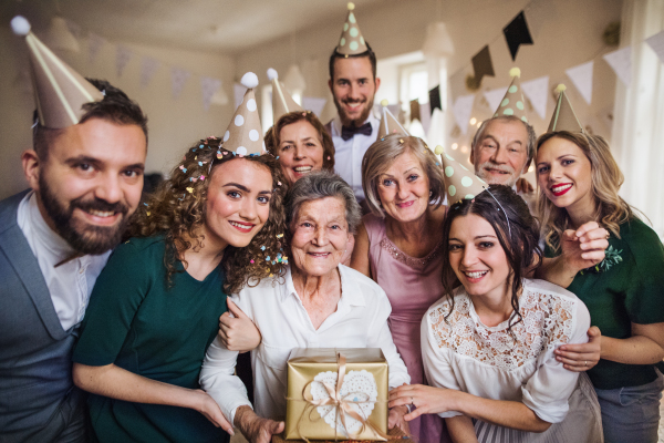 A portrait of multigeneration family with presents standing indoor on a birthday party.