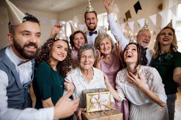 A portrait of multigeneration family with presents standing indoor on a birthday party.