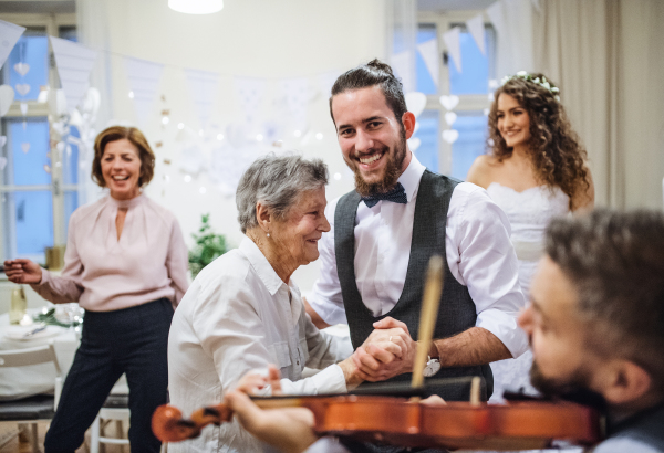 A young bridegroom dancing with great grandmother on a wedding reception.