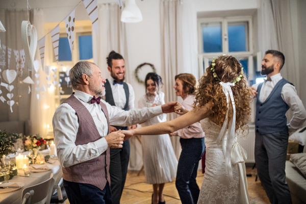 A young bride dancing with father or grandfather and other guests on a wedding reception.