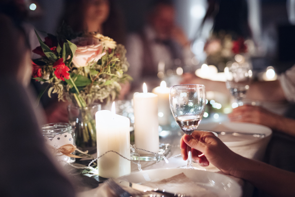 A midsection of family sitting at a table on a indoor birthday party, holding glasses.