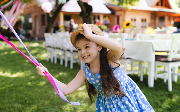 Small girl outdoors in garden in summer, playing with balloons. A celebration concept.