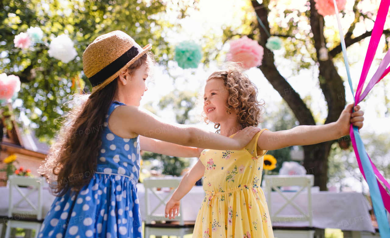 Small children outdoors in garden in summer, playing. A celebration concept.