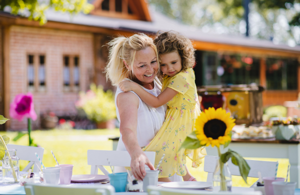 Grandmother holding small girll outdoors on garden party in summer, celebration concept.