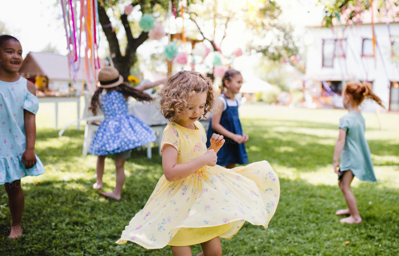 Small children standing outdoors in garden in summer, playing. A celebration concept.