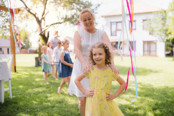 Grandmother with small girll outdoors on garden party in summer, playing. Celebration concept.