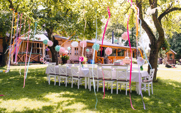 A table set for kids birthday party outdoors in garden in summer, celebration concept.