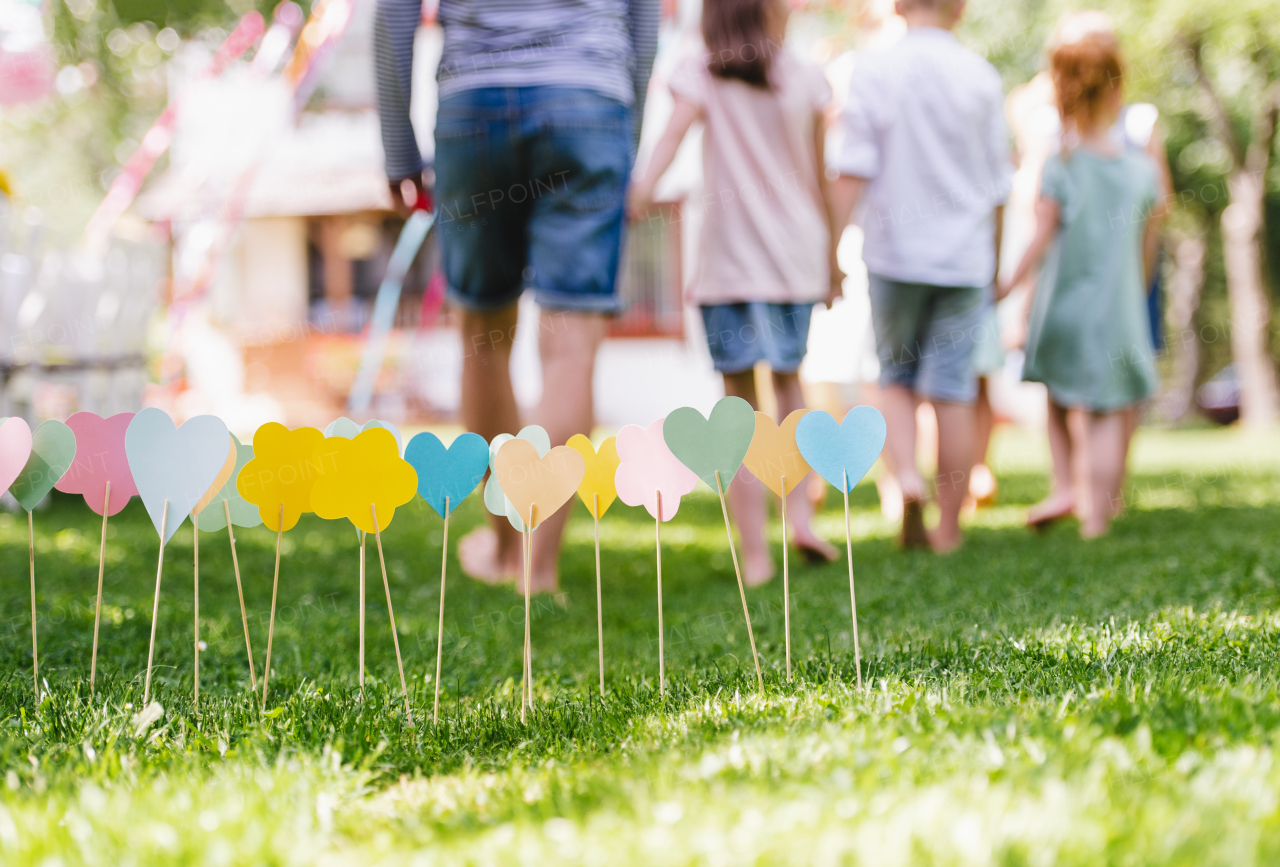 Rear view of man with small children walking outdoors on garden party. Copy space.