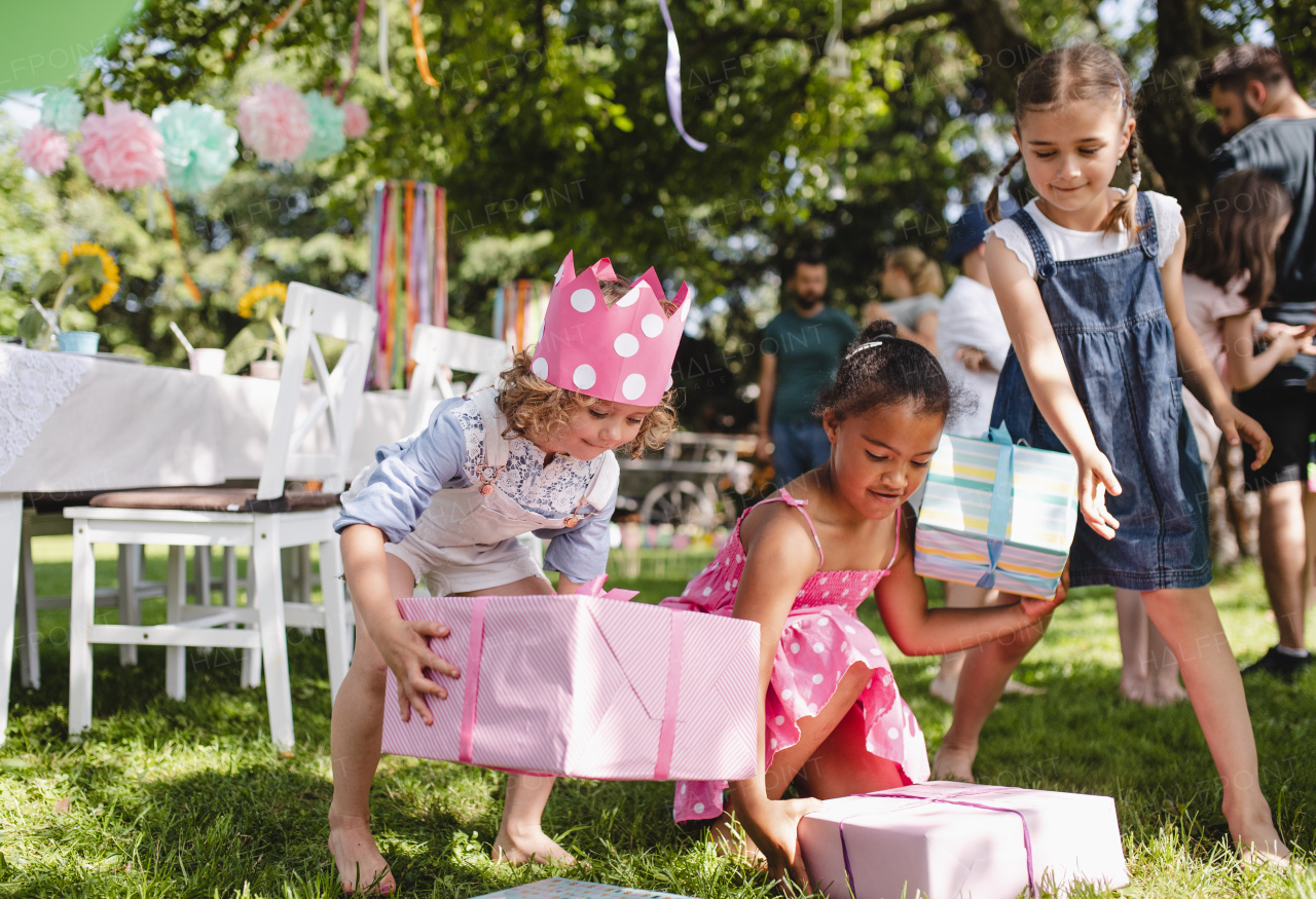 Group of small girls with presents outdoors in garden in summer, playing.