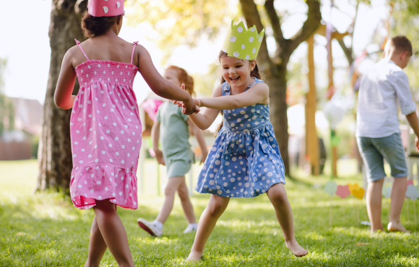 Small children standing outdoors in garden in summer, playing. A celebration concept.