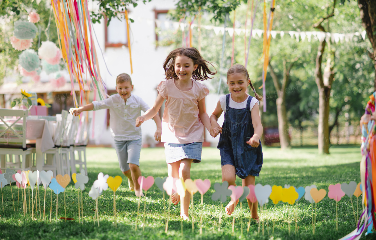 Small children outdoors in garden in summer, running when playing. A celebration concept.