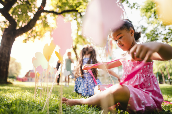 Small children outdoors in garden in summer, playing. A celebration concept.