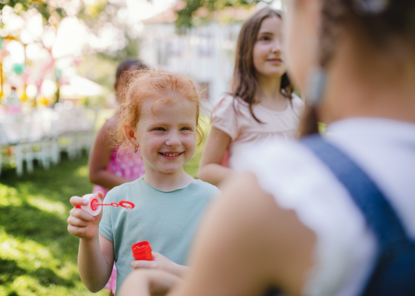 Small children outdoors in garden in summer, playing with bubbles. A celebration concept.