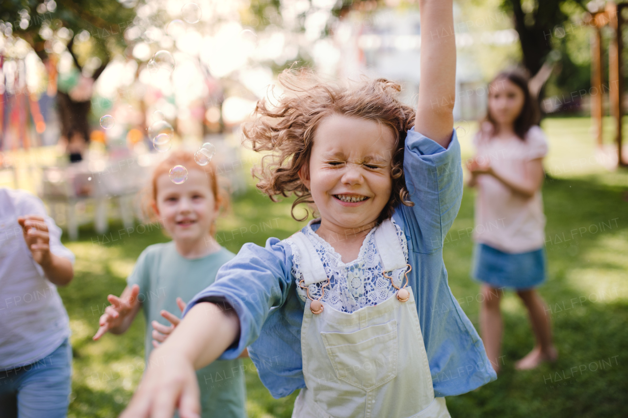 Small children standing outdoors in garden in summer, playing. A celebration concept.