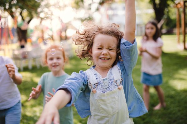 Small children standing outdoors in garden in summer, playing. A celebration concept.