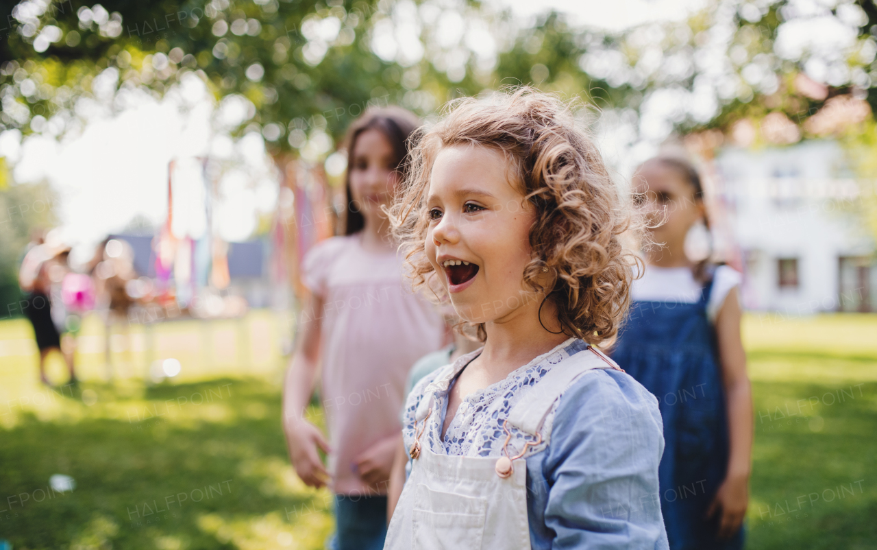 Small children outdoors in garden in summer, playing. A celebration concept.