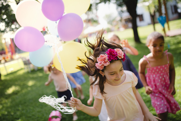 Small children running outdoors in garden in summer, playing. A celebration concept.