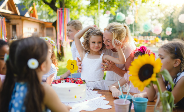 Group of small children sitting at the table outdoors on garden party.