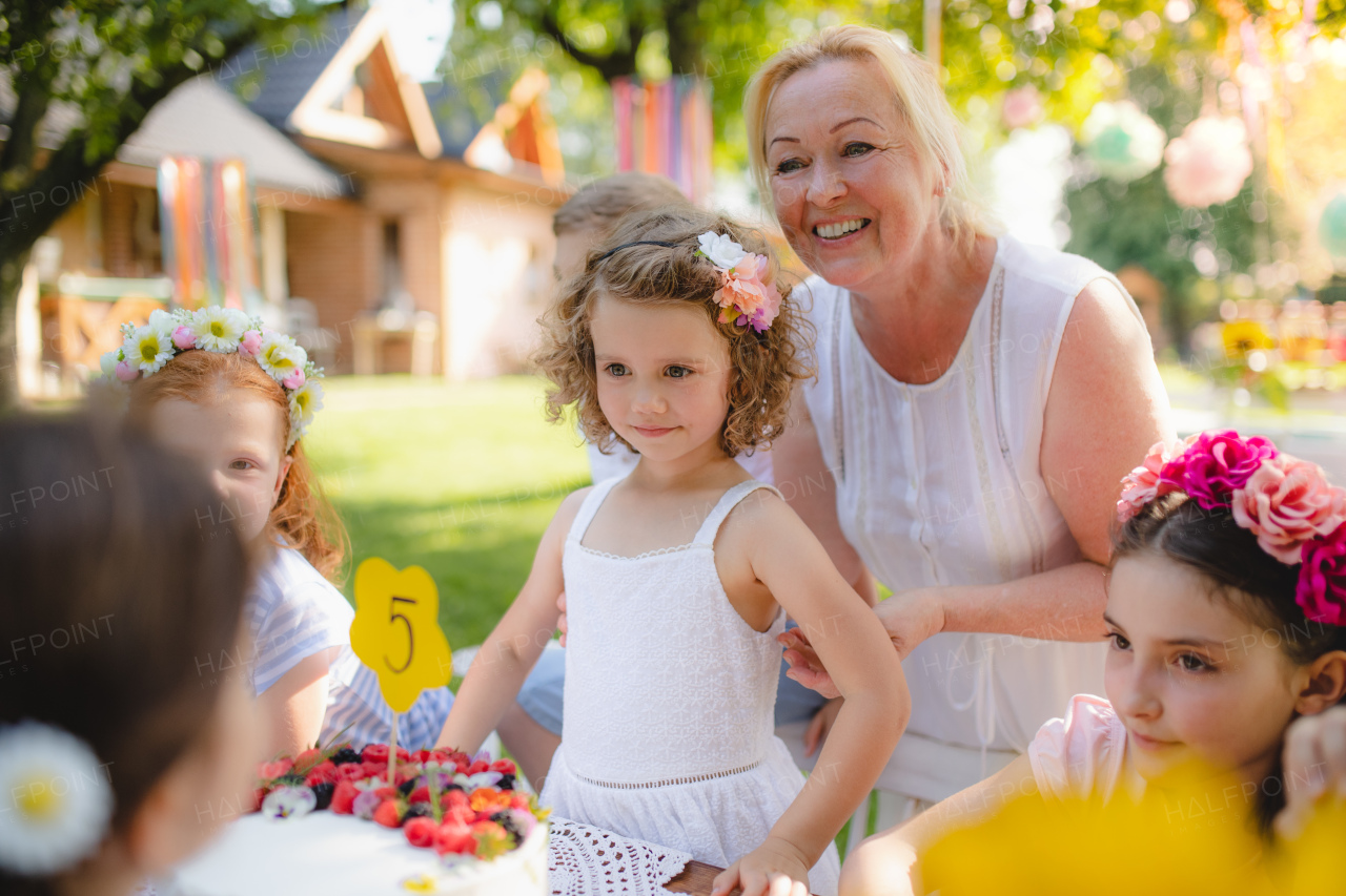 Group of small children sitting at the table outdoors on garden party.