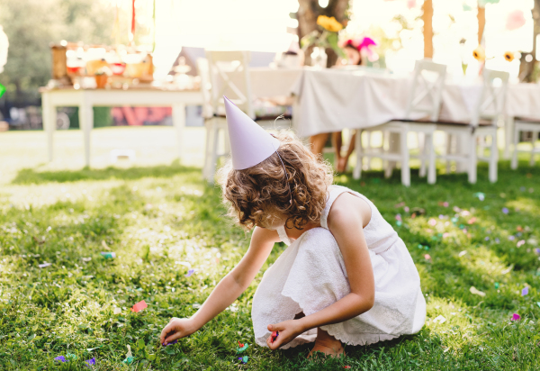 Small girl playing outdoors on garden party in summer, a celebration concept.