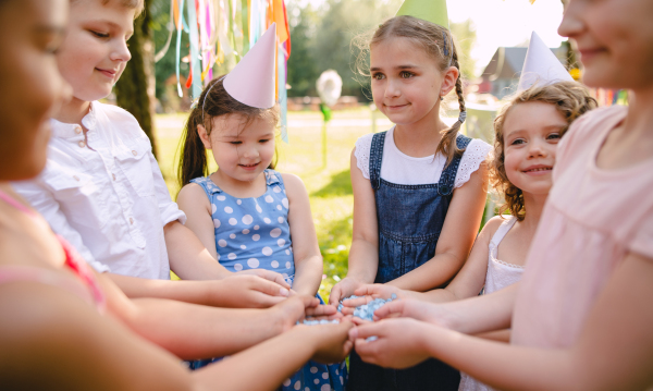 Children playing outdoors on birthday party in garden in summer, celebration concept.